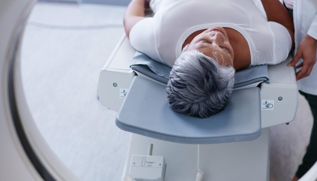 a woman lies on an MRI machine bed before entering the machine