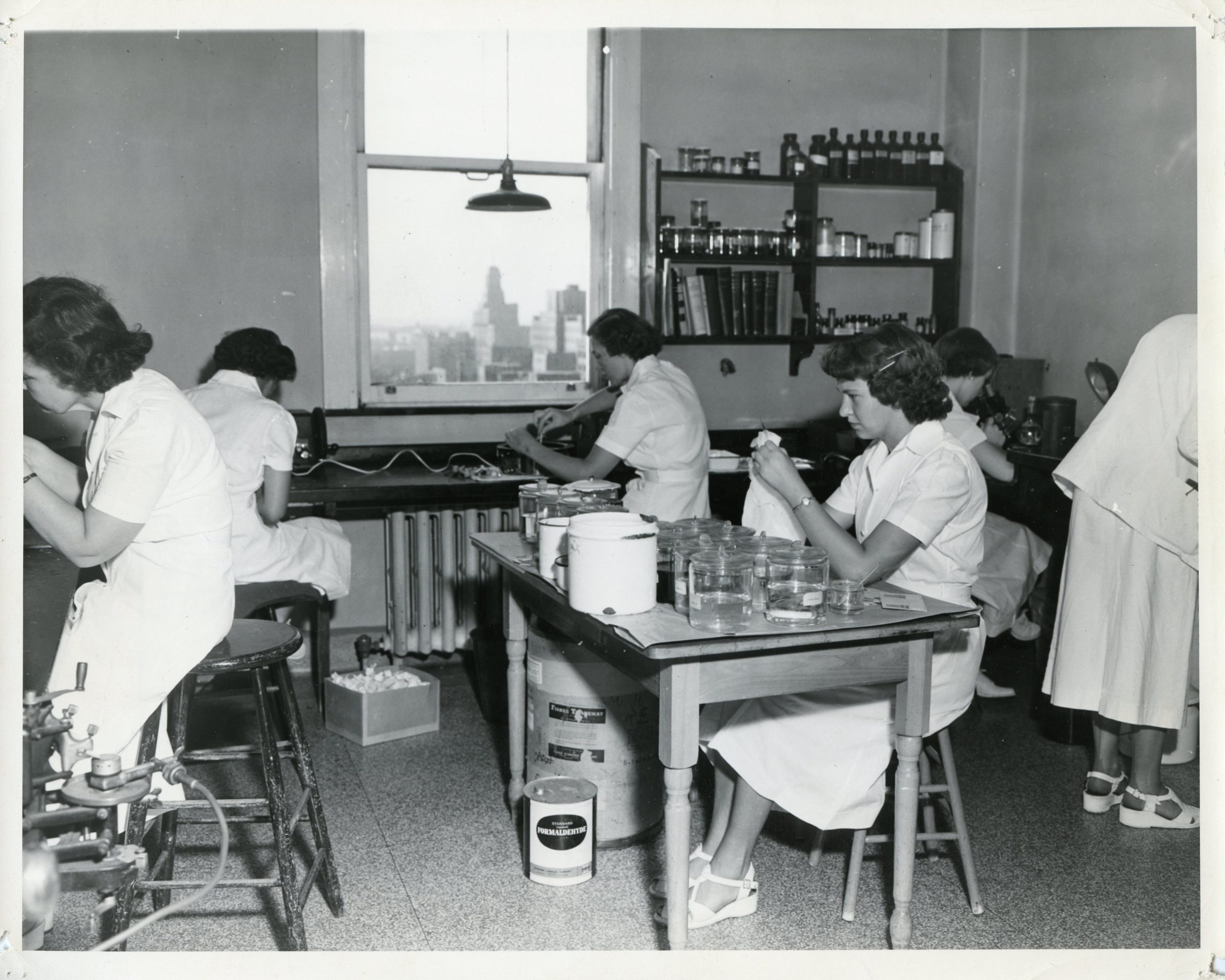 black and white photo of several lab technicians hard at work at different tables