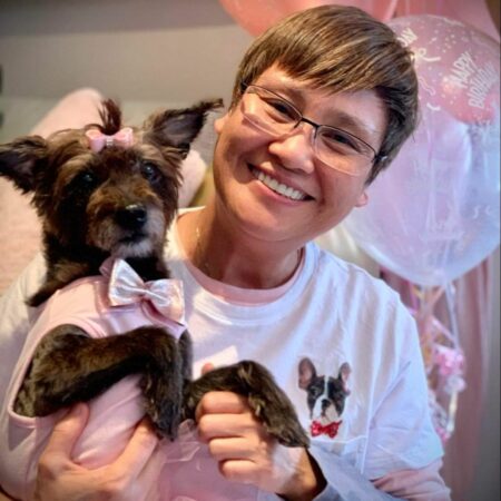 Lelia Mondejar holds a small dog in a pink outfit.