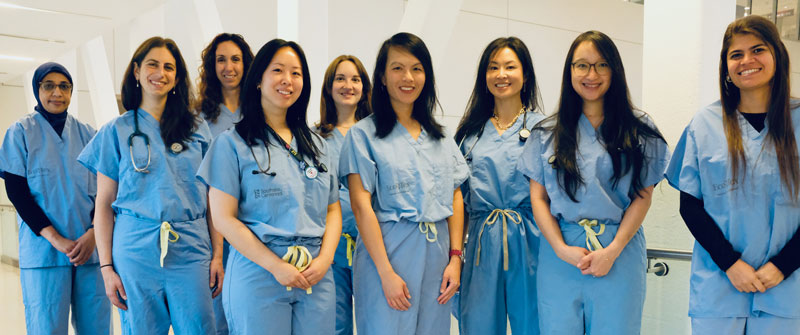 A group of clinicians in scrubs standing in a hallway
