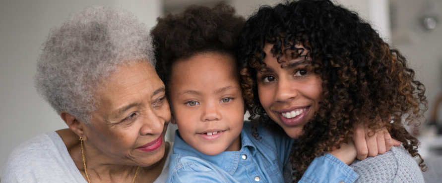 A grandma of African descent is laughing and spending time with her daughter and granddaughter.